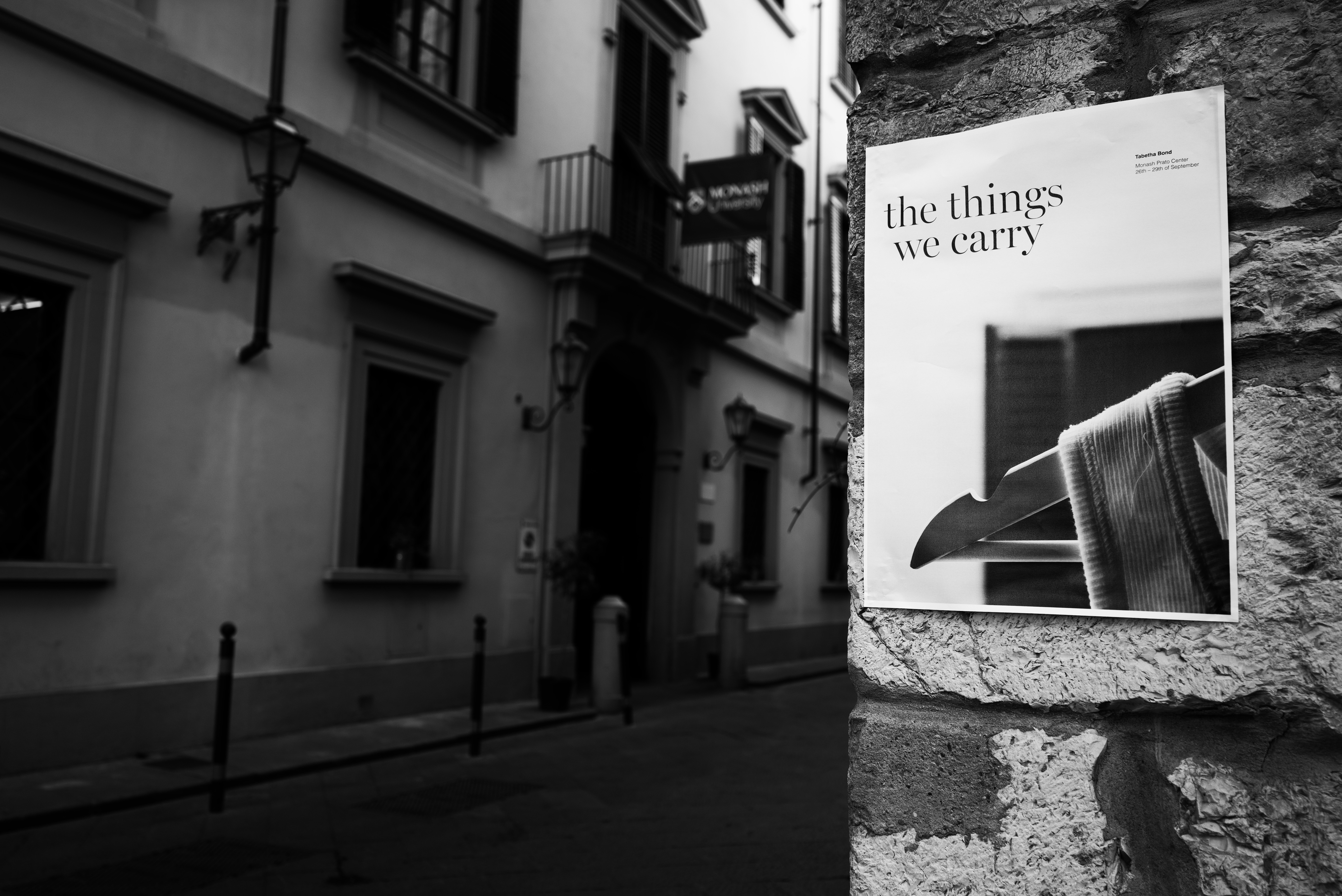 Black and White image: Poster on wall outside building