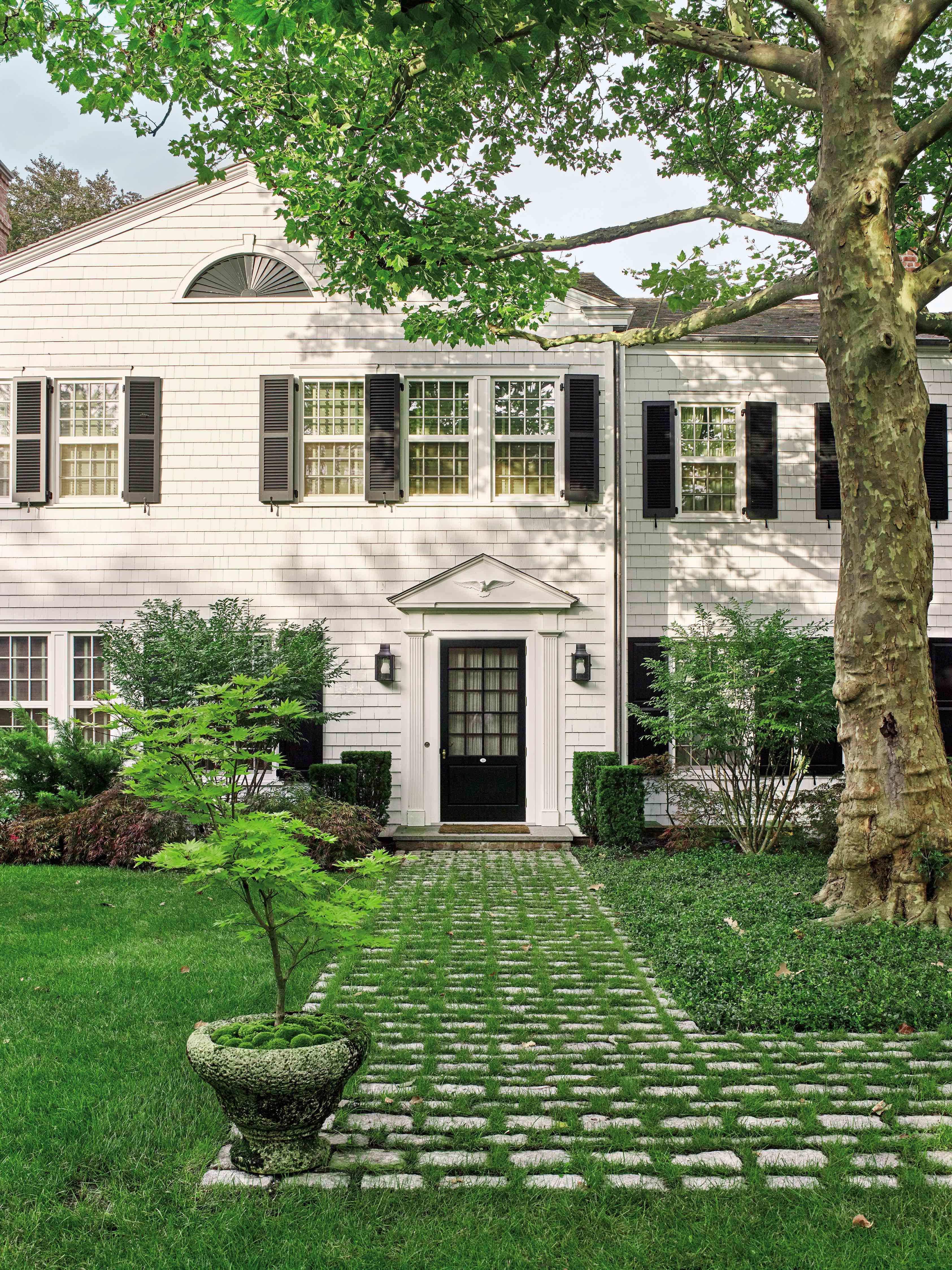 Exterior view of white shingle Academy house with black shutters and manicured green lawn, photographed by Studio Wisdom