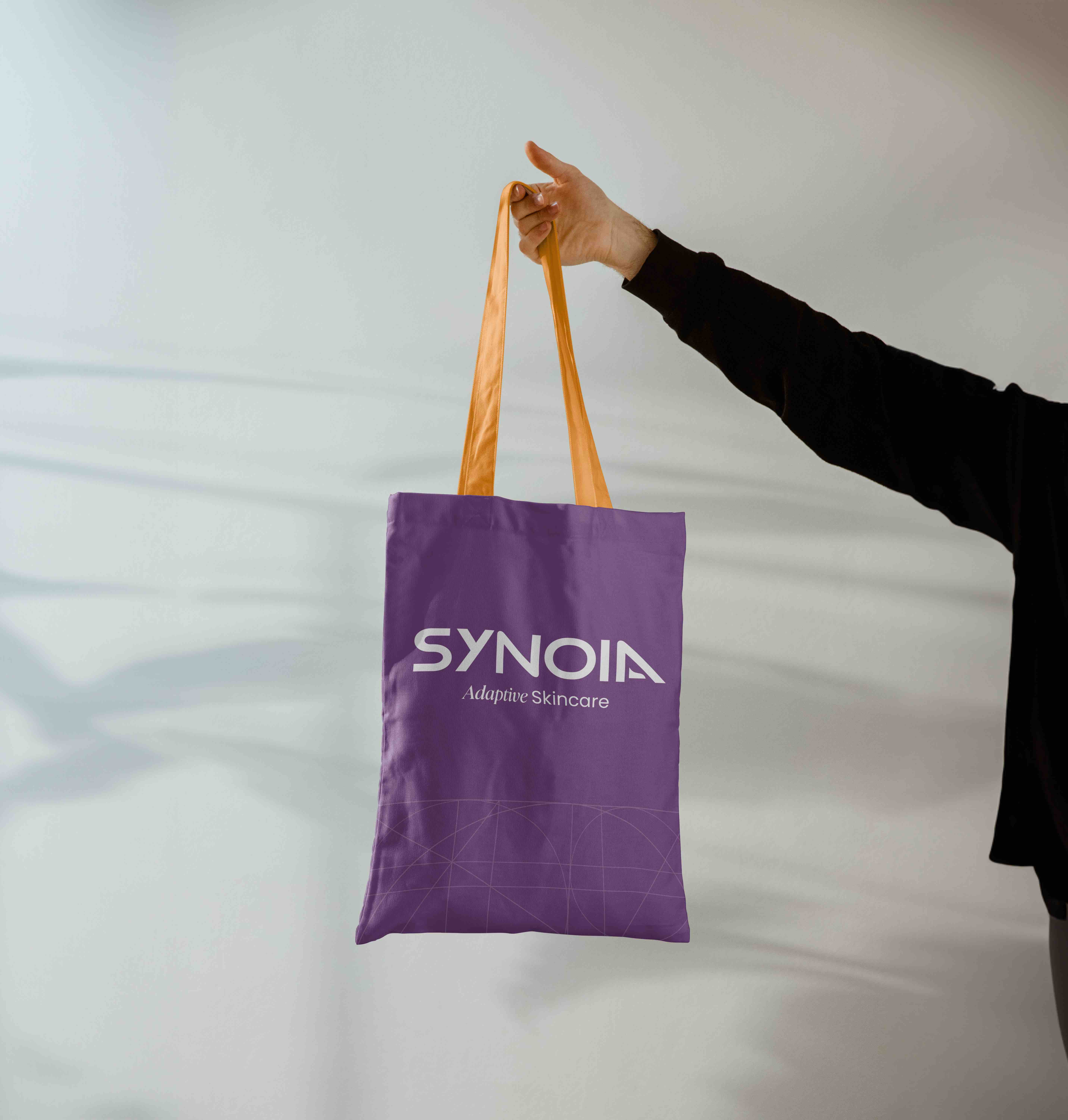 Synoia Technologies branded tote bag design in purple with logo and tagline, designed by Studio Wisdom.