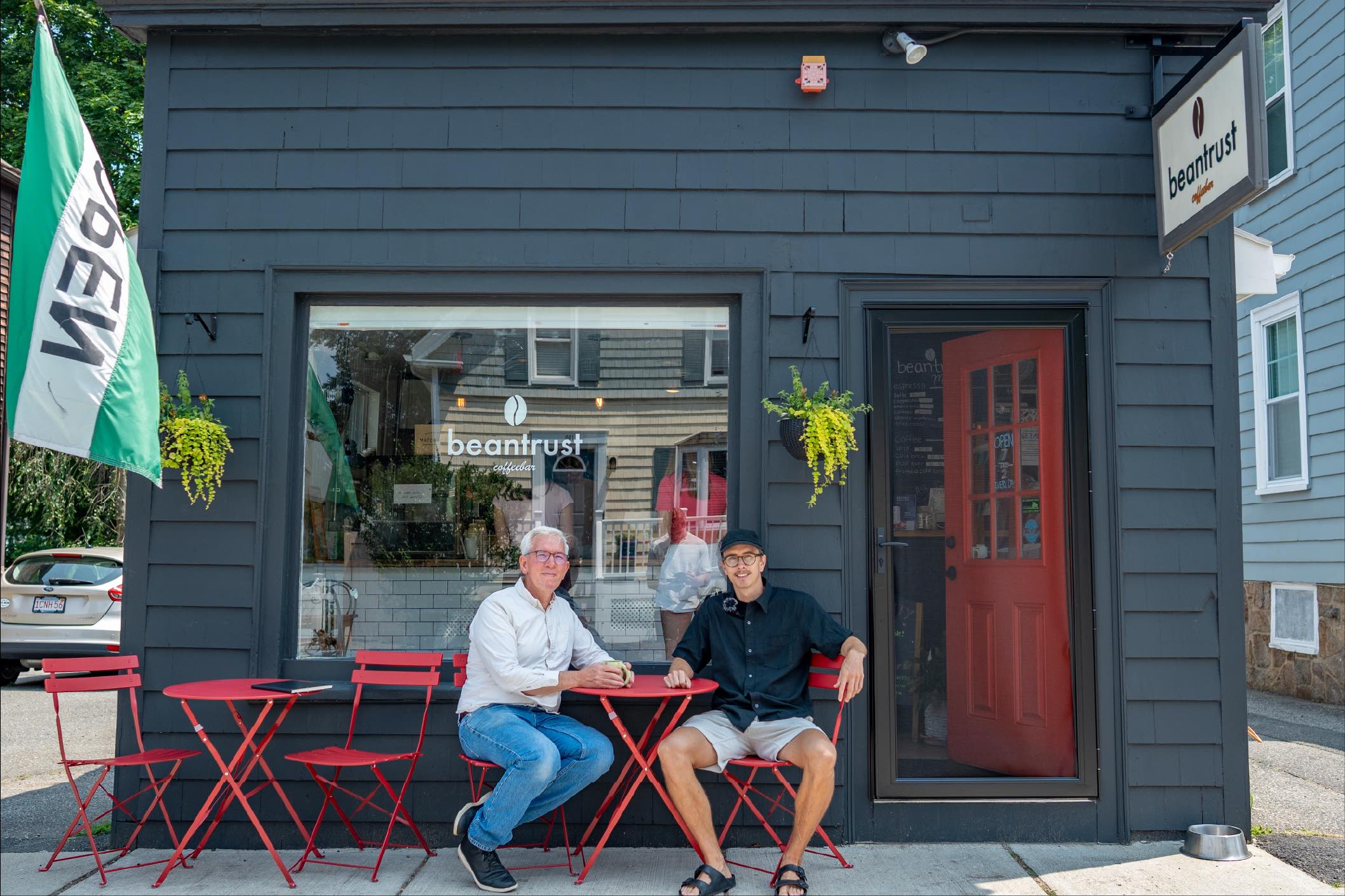 Beantust Coffeebar storefront with founder Erik and Tommy Wisdom seated outside, showcasing Studio Wisdom’s café rebranding work