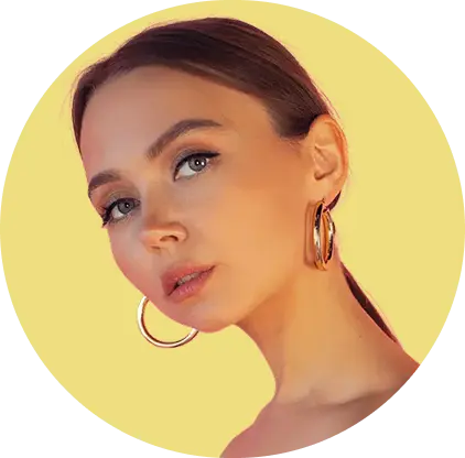 A woman with long hair pulled back, wearing large hoop earrings, against a bright yellow circular background.