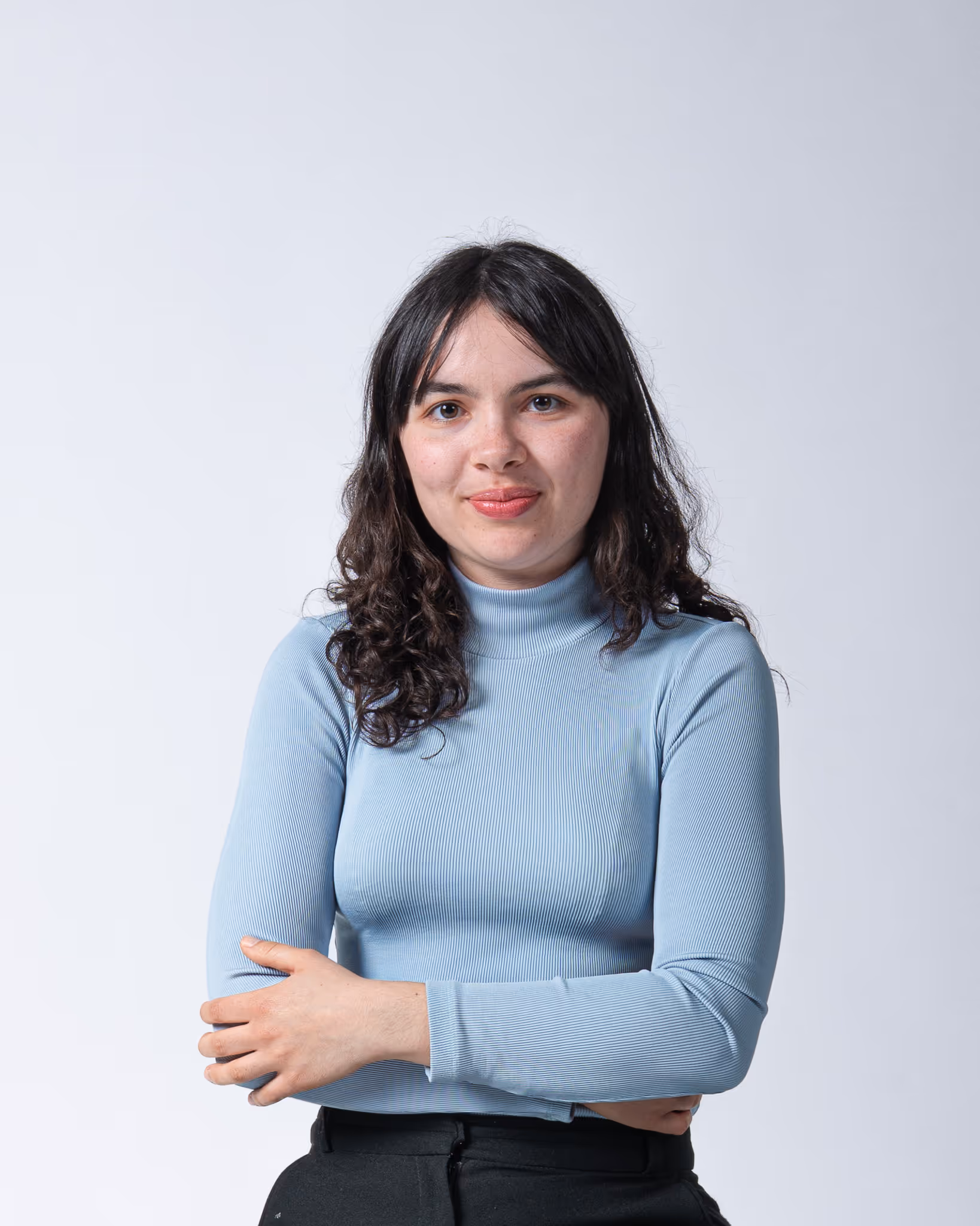 Portrait in einem Fotostudio von einer Person, die die Arme verschränkt und in die Kamera lächelt