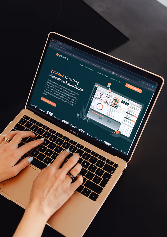Eine Person tippt auf einen Laptop, darauf die Startseite von goconut.com