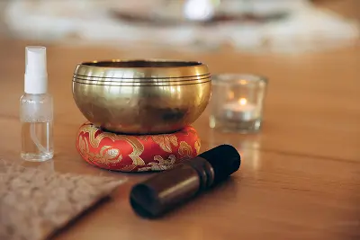 Klangschale, Kerze und Raumsprays auf einem Tisch