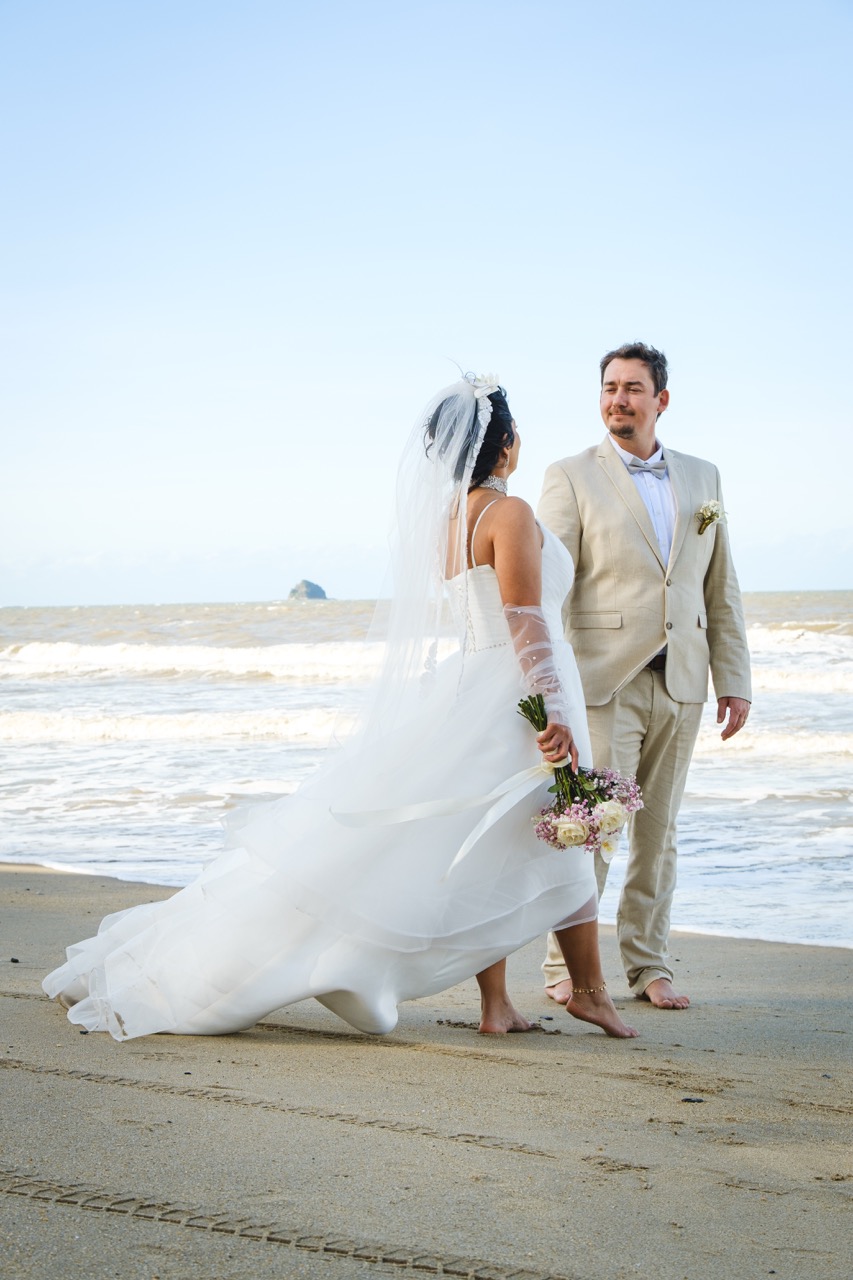 Couple in wedding, in the beach of palm cove look herselves with naked feet