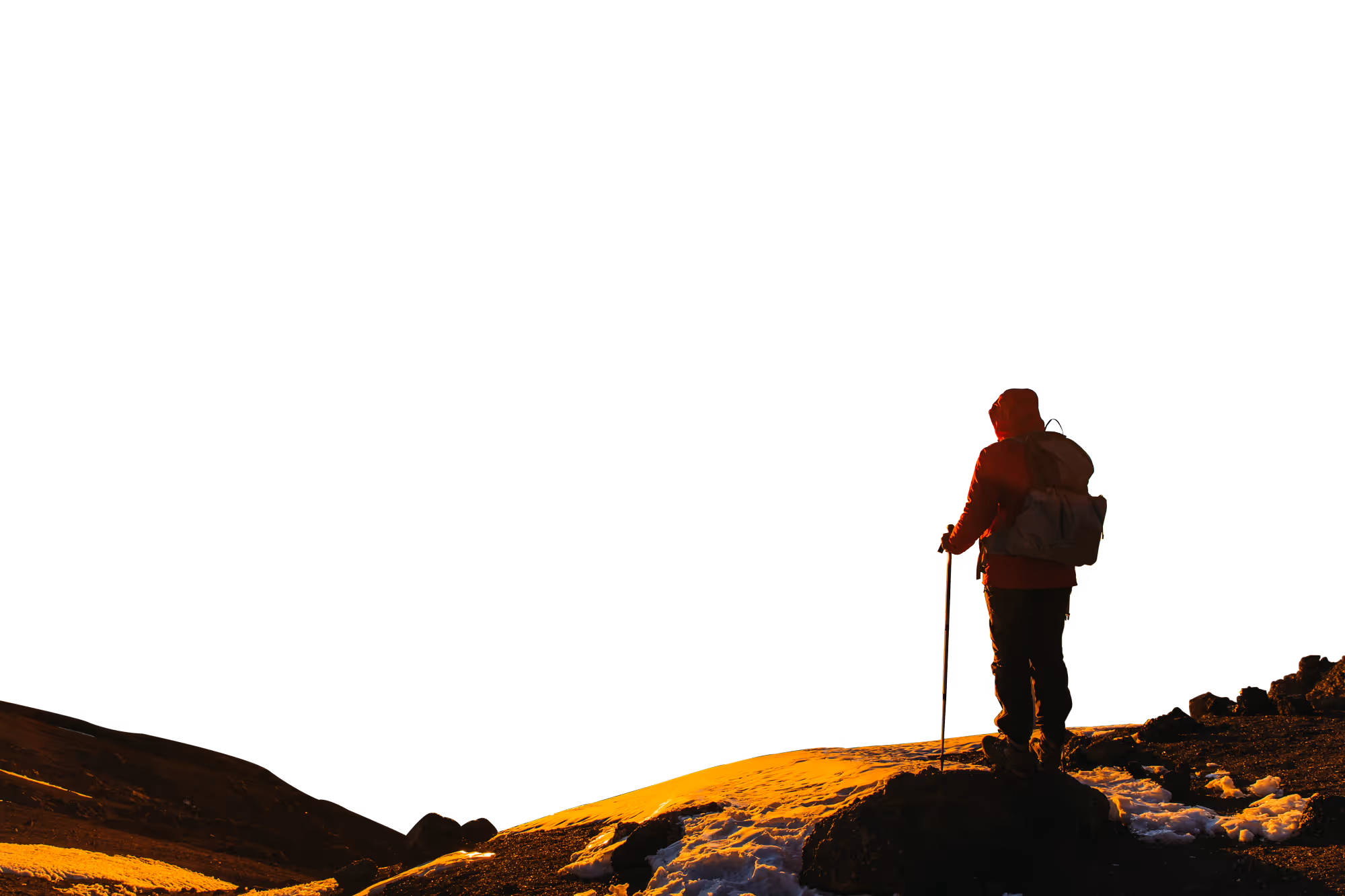 A hiker stands on the summits overlooking a sunset