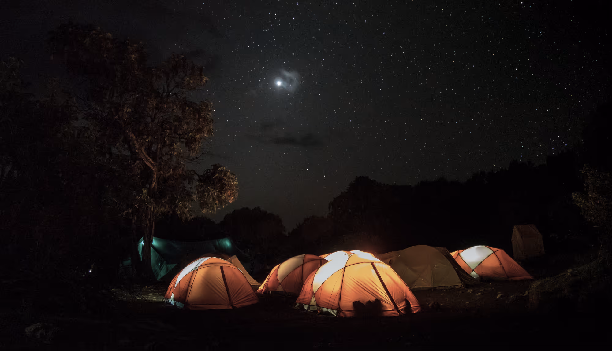 A group of glowing cozy tents at night, during a mount Kilimanjaro climb