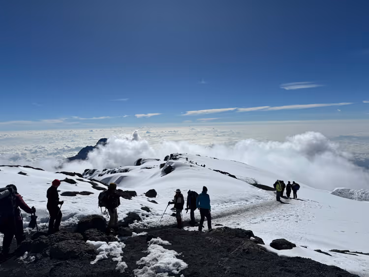 A group of climbers trekking up the snow covered peaks of mount Kilimanjaro with Uncharted Summits.