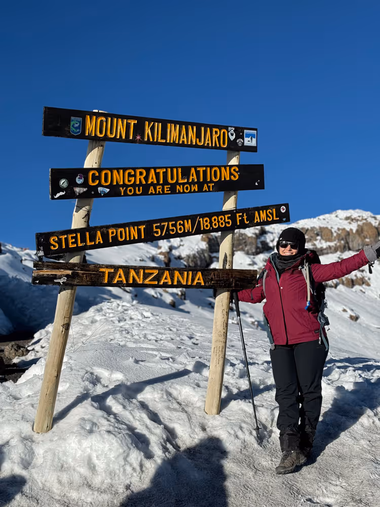 Posing with the sign at Stella Point, Mount Kilimanjaro, on an Uncharted Summits Climb