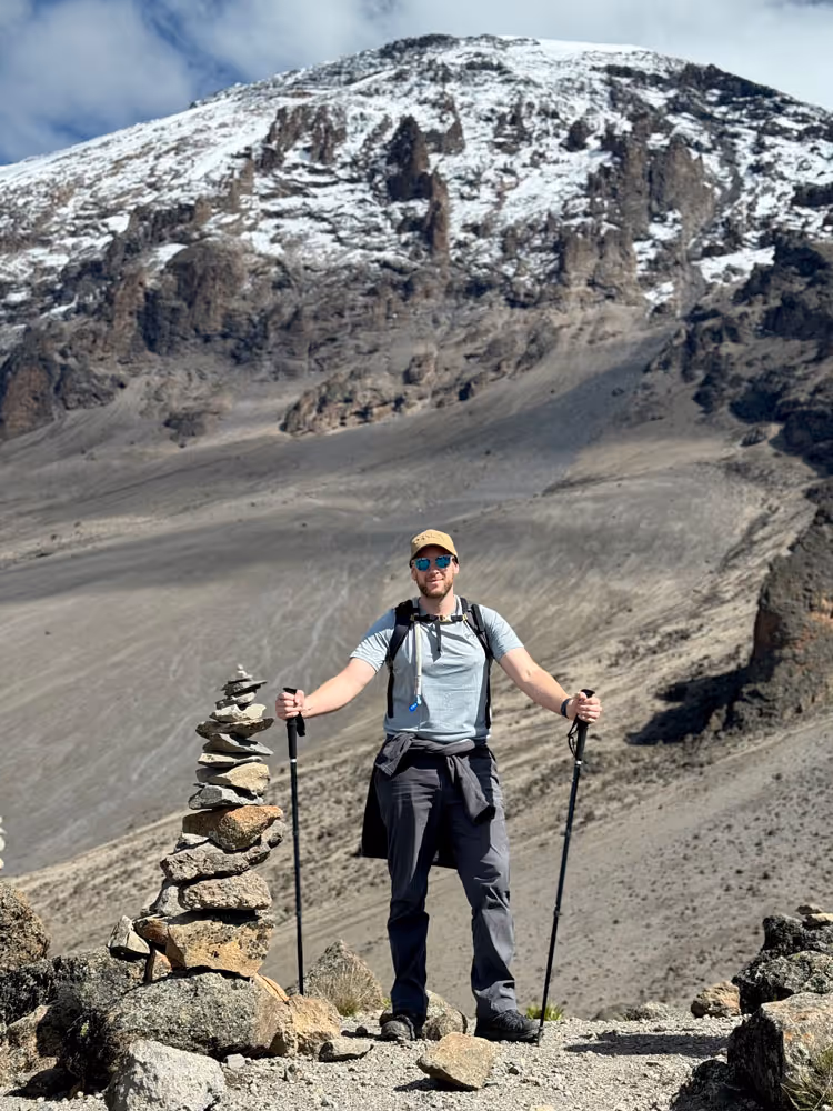 Hiker posing in front of a peak on Mount Kilimanjaro on an Uncharted Summits climb