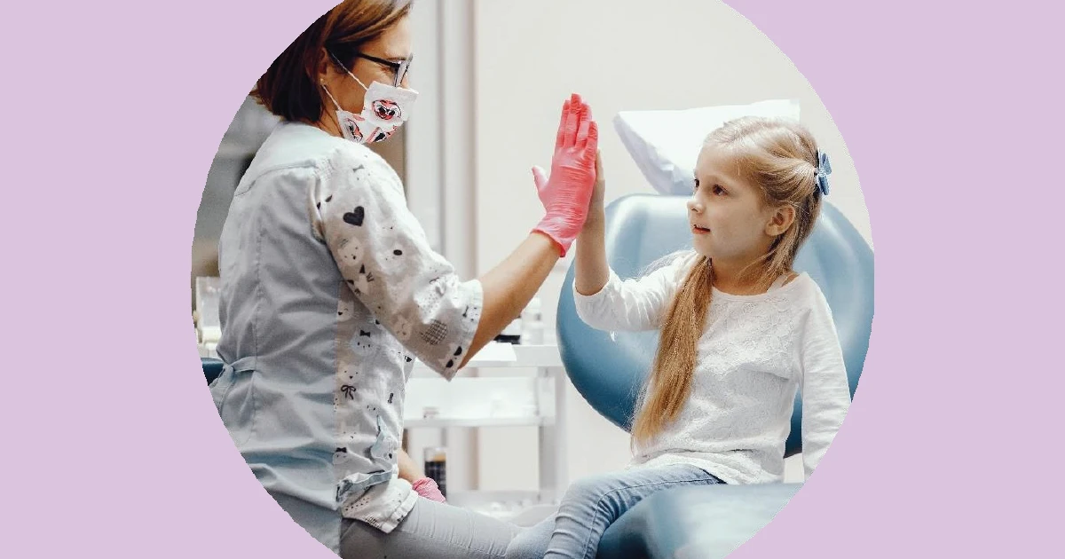 A woman wearing a mask and a white shirt is holding a toothbrush.