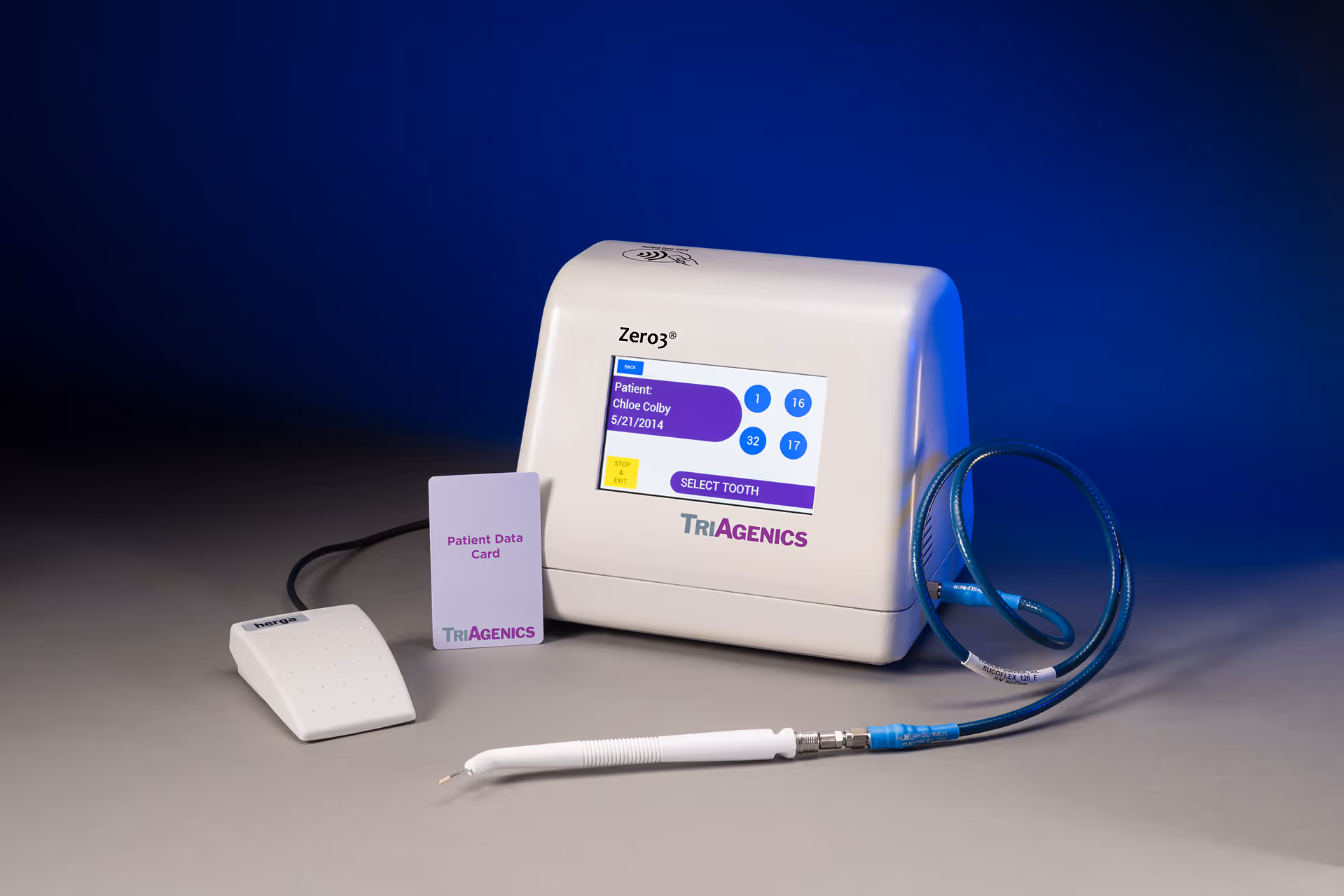 TriAgenics Zero3® medical device setup showing the main touchscreen unit displaying patient info, connected handpiece, patient data card, and foot control, used for minimally invasive wisdom tooth treatment.