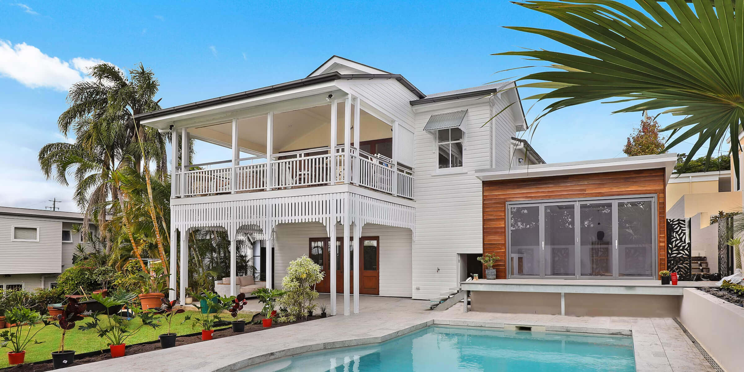 A large white house with a pool in front of it.