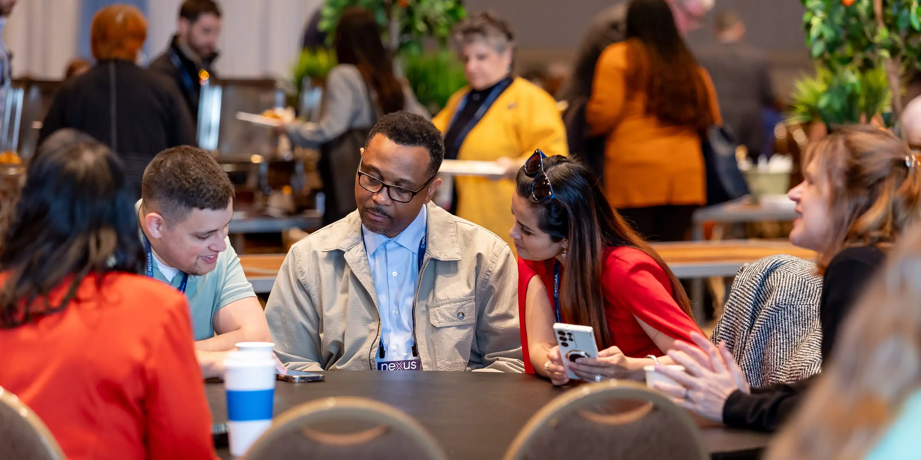 Conference participants sitting round a table, sharing information on a mobile device