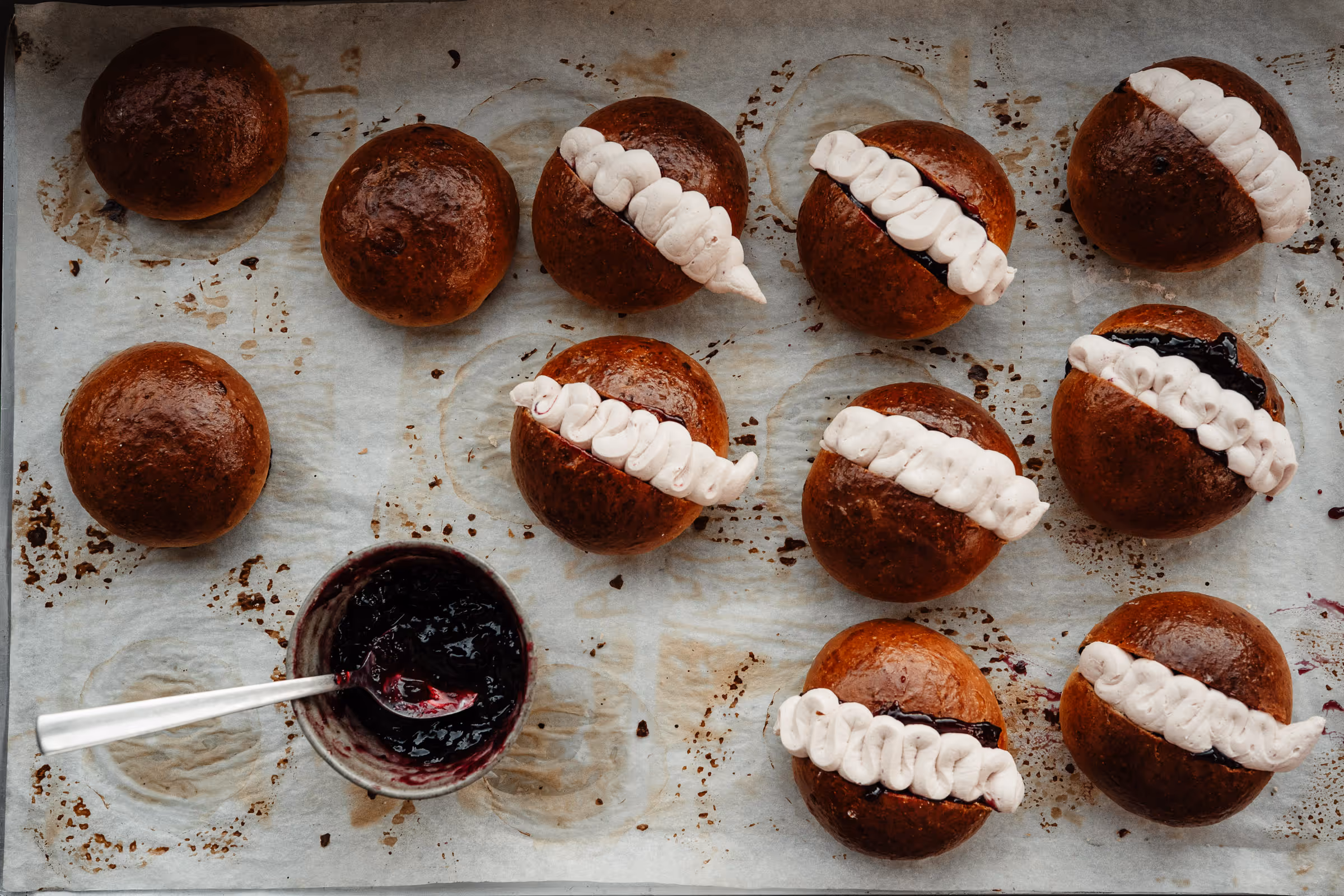 Flori Bakery tray of freshly baked buns on a tray being filled with handmade jam and hand piped with fresh cream