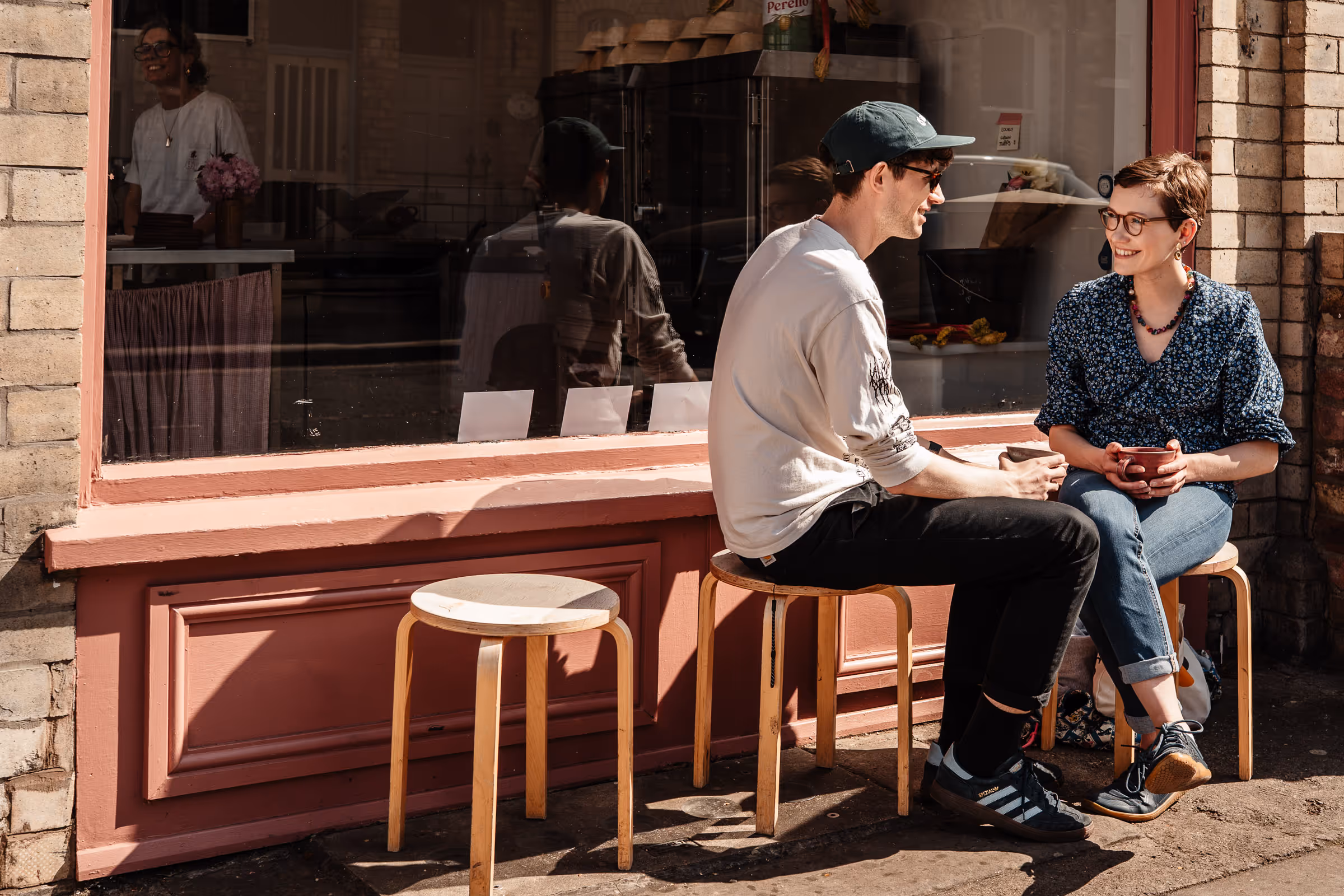 Happy coupel sat outside Flori bakery with barista coffees in hand