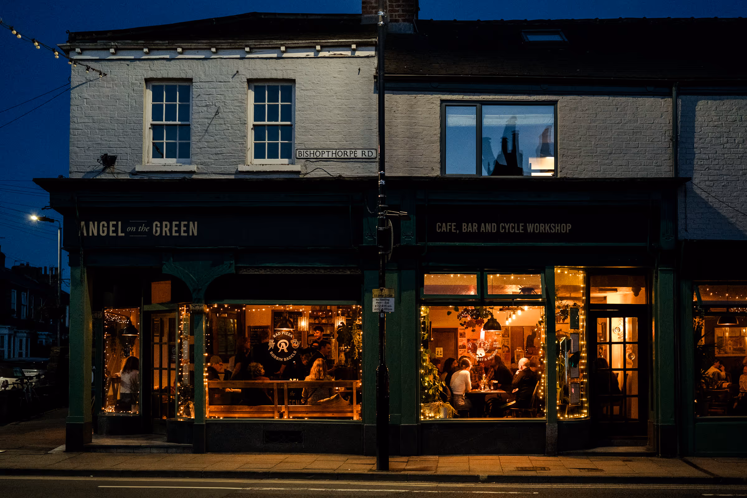 Nightime photo of Angel On The Green with golden glow of  inside and twinkling lights