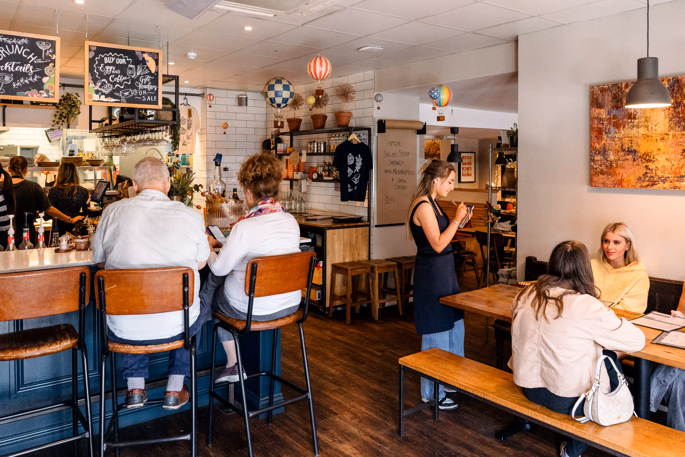 Warm bright restaurant interior, at Robinson's with beautiful waiting staff tending to table of guests