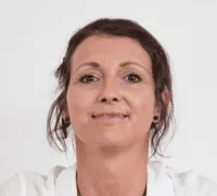 Porträt von Elisabeth Poth mit dunklem Haar und dezentem Lächeln, vor neutralem weissem Hintergrund, trägt ein weisses Oberteil.