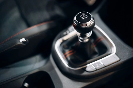 Car transmission gear shift lever in a modern vehicle interior with sleek black and metallic design.