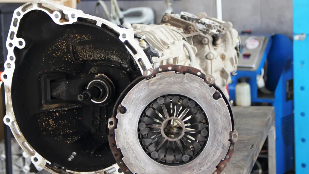 Professional transmission mechanic working on a disassembled clutch and transmission system in a workshop