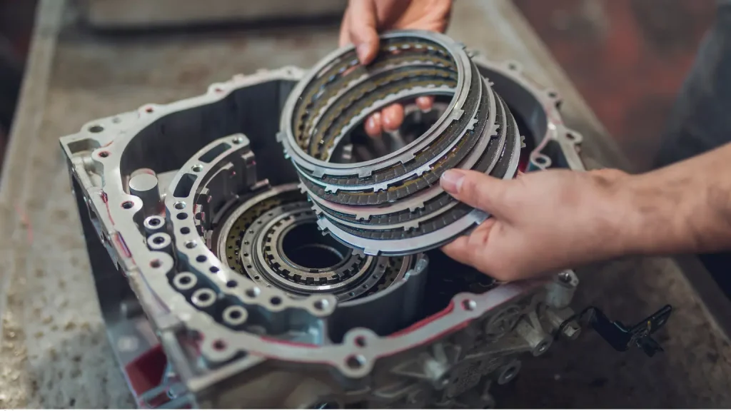 Mechanic handling clutch plates during a car transmission rebuild process