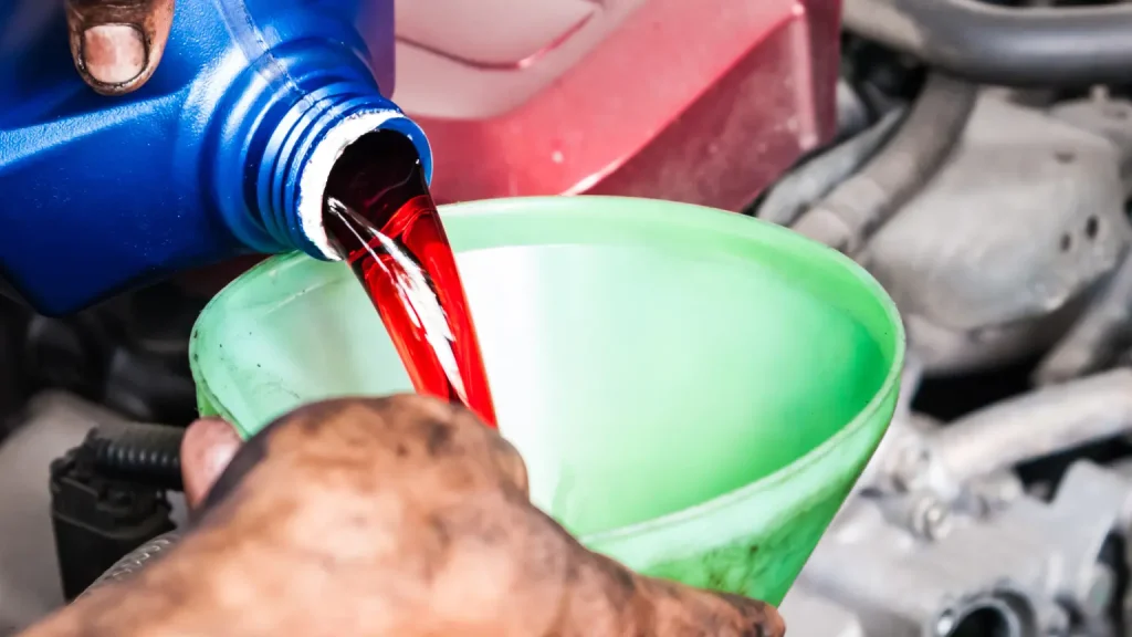 Red transmission fluid being poured into a funnel during vehicle maintenance