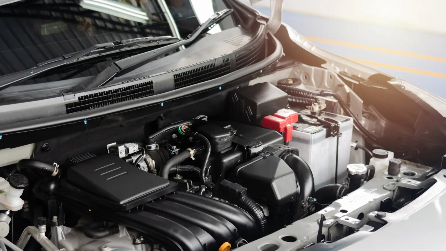 Auto transmission repair with a focus on a clean, modern engine compartment featuring a visible battery and wiring.
