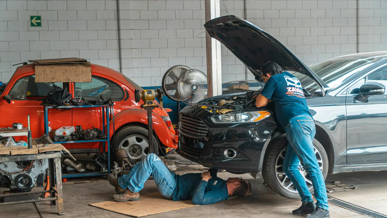 Local transmission shop with mechanics inspecting and repairing cars in a fully equipped garage