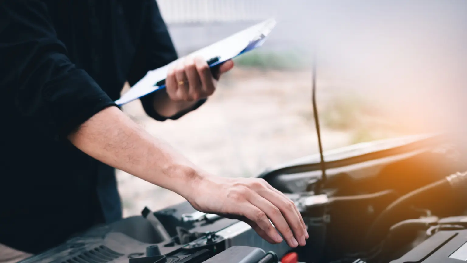 Transmission specialist performing engine diagnostics with clipboard during vehicle inspection