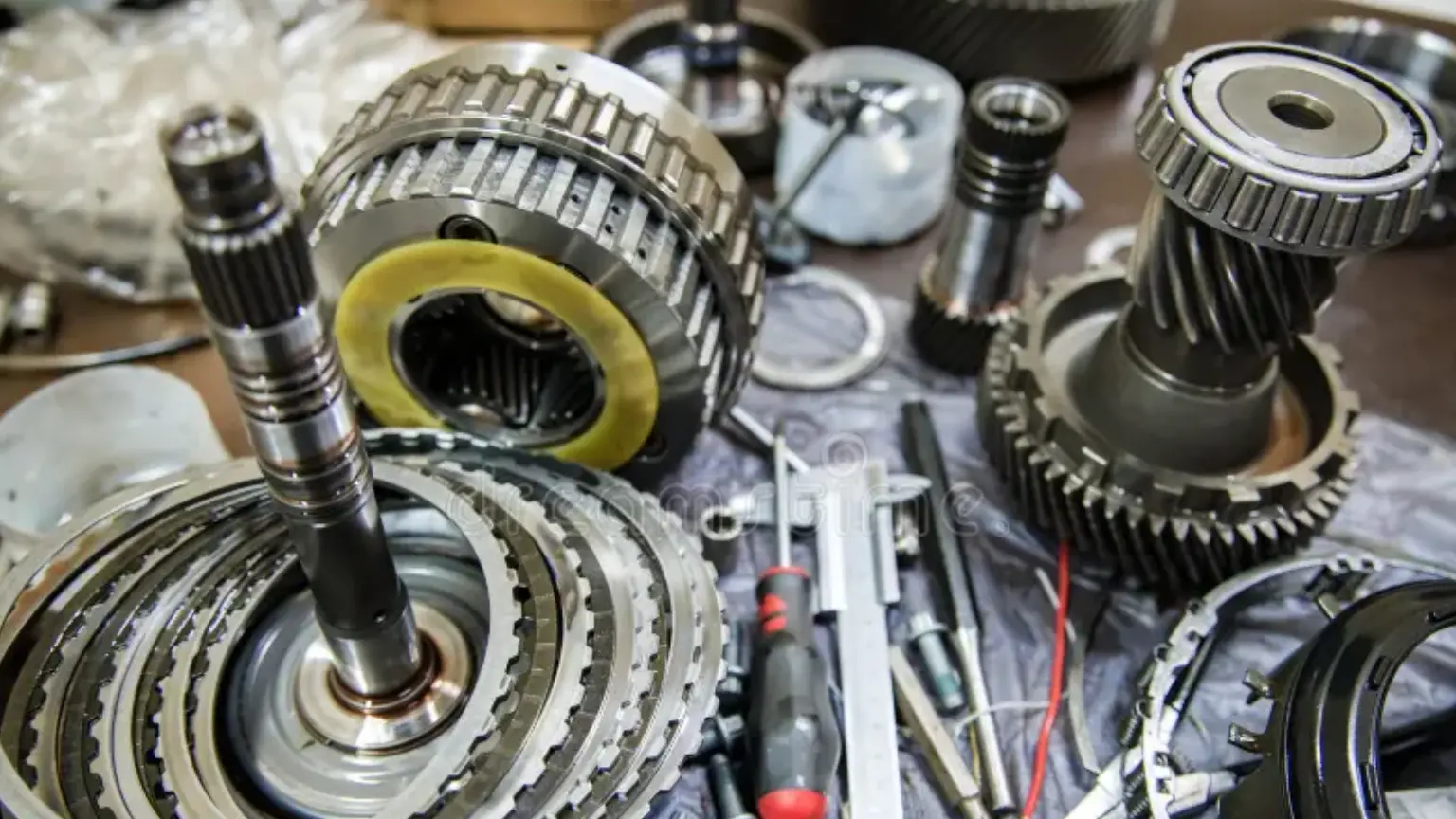 Transmission repair shop tools and disassembled gearbox components laid out on a workbench