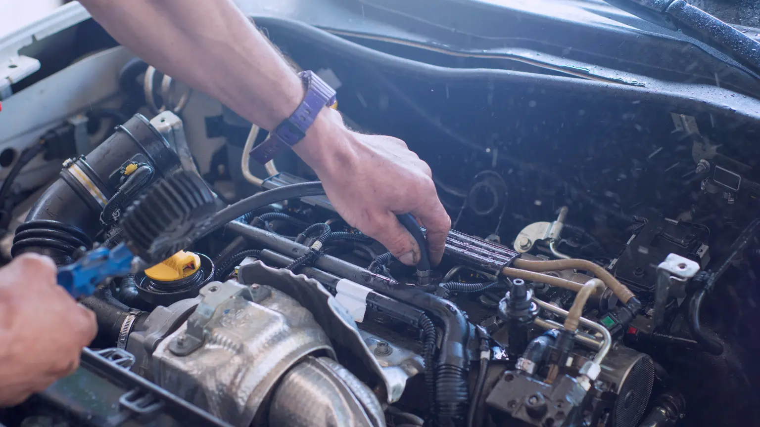 Transmission mechanic working under the hood inspecting hoses and electrical connections