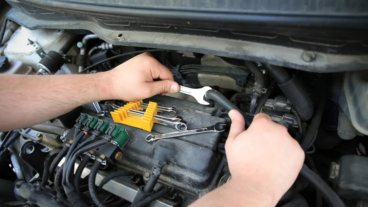 Auto transmission repair with mechanic tightening connections on engine using various wrenches