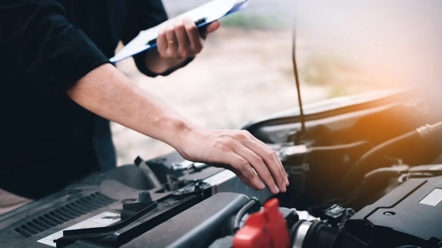 Trusted transmission shop technician inspecting engine bay with clipboard for diagnostic or repair assessment.