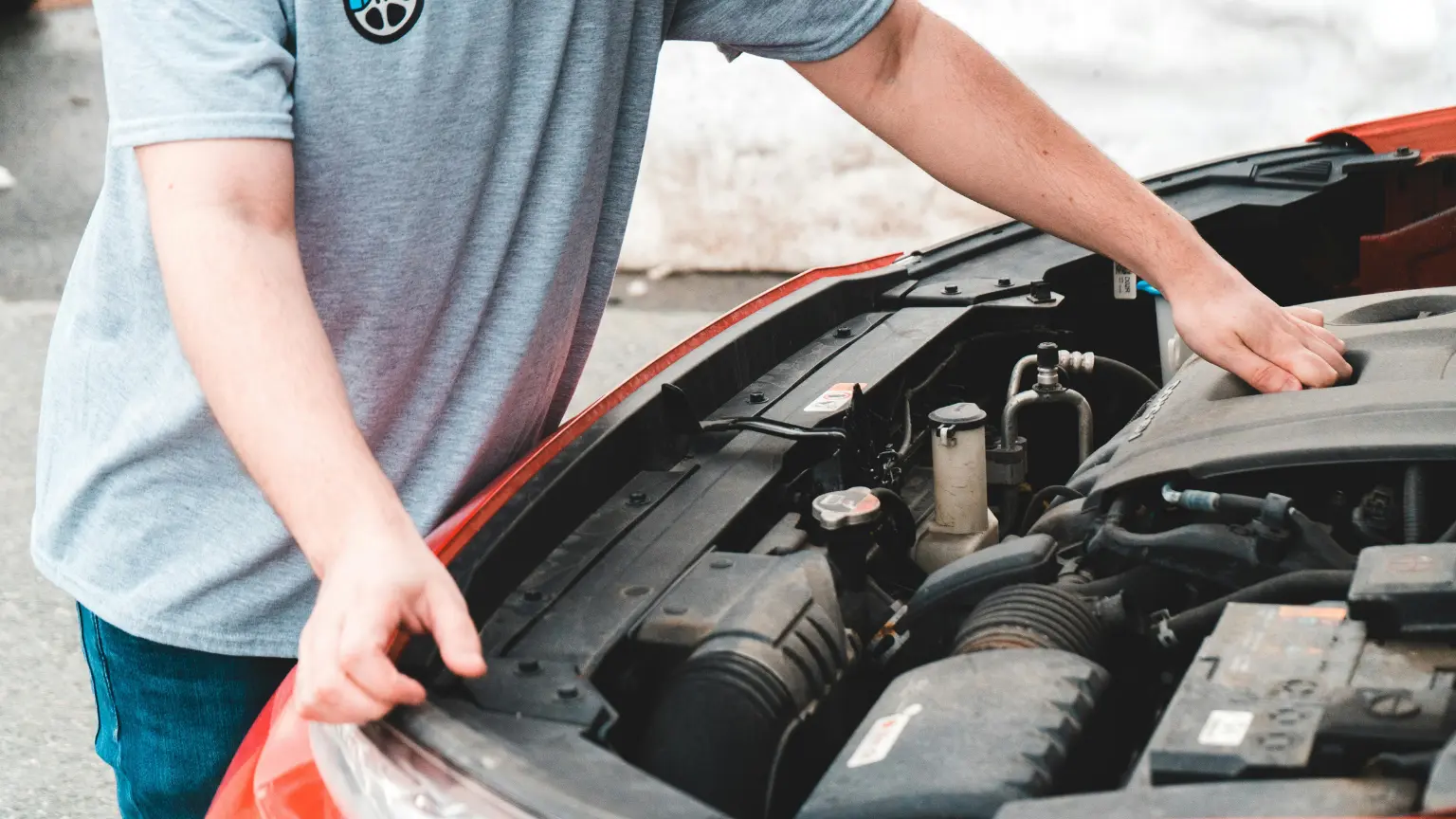 Transmission repair shops assist customers as a man checks under the hood of a car in an outdoor setting.