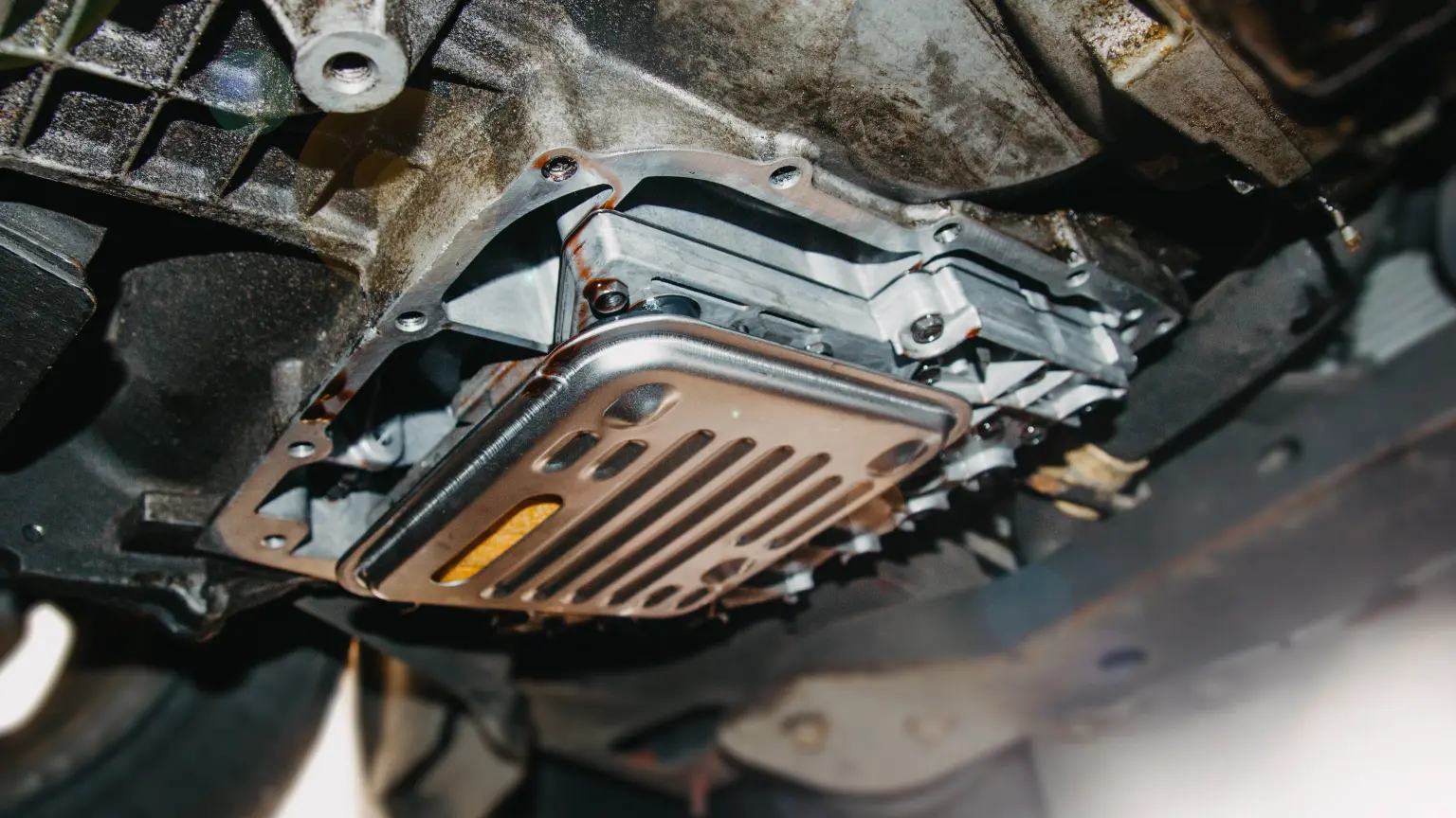 Transmission oil pan seen from underneath a car on a lift during a fluid service