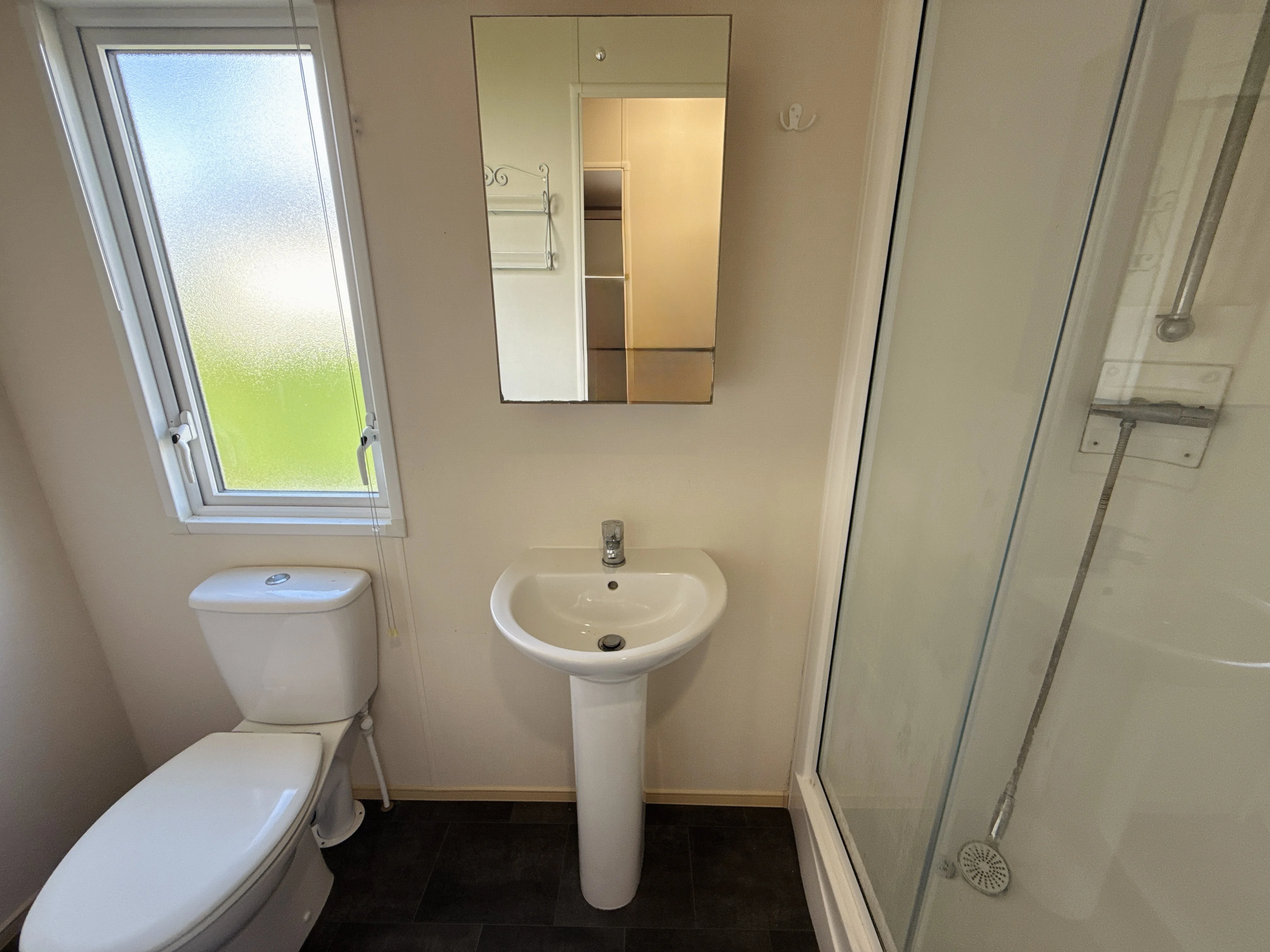 Clean, minimalist bathroom with white fixtures, mirror, and frosted window