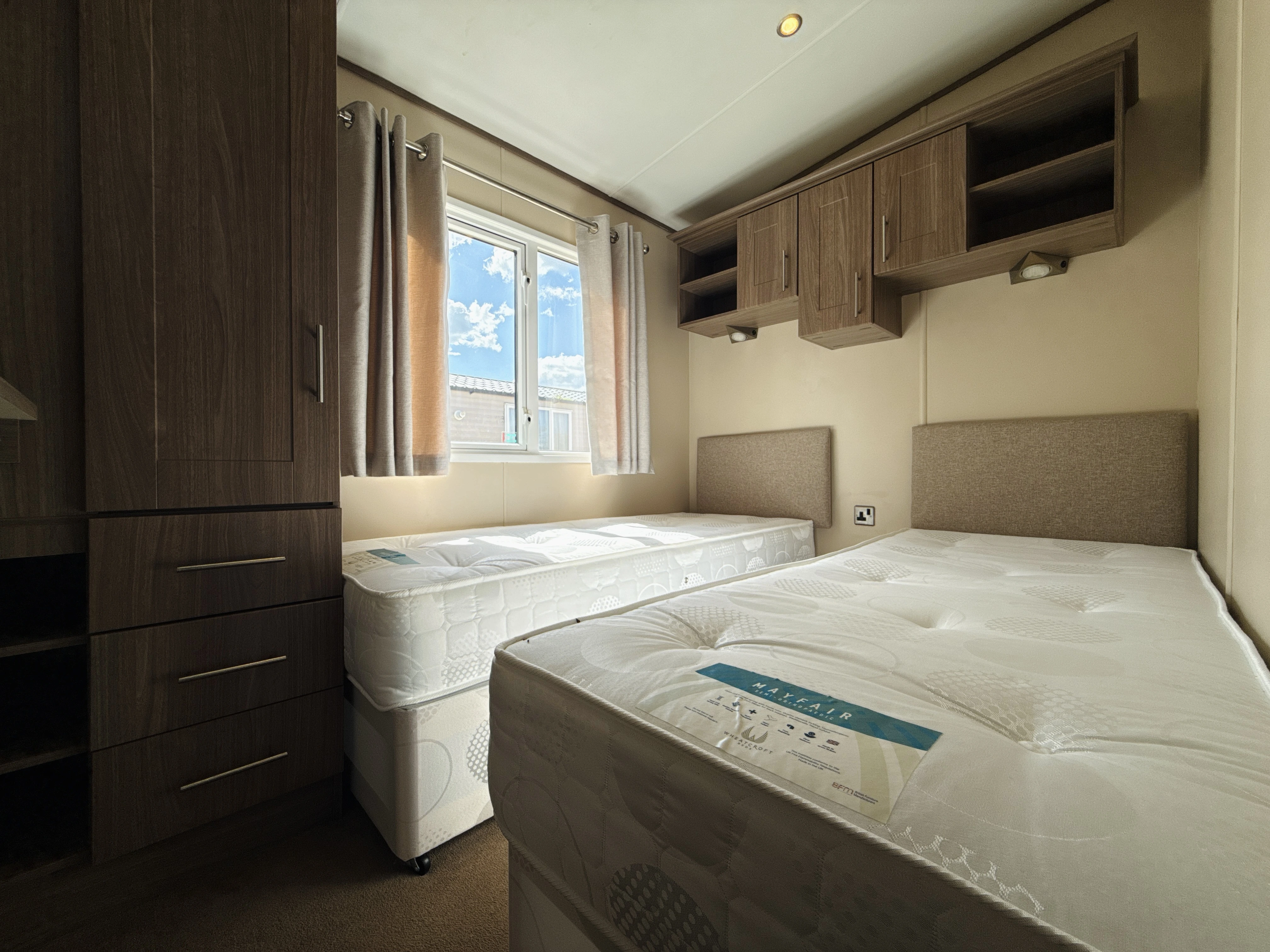 Twin bedroom in a mobile home with wooden cabinets and window