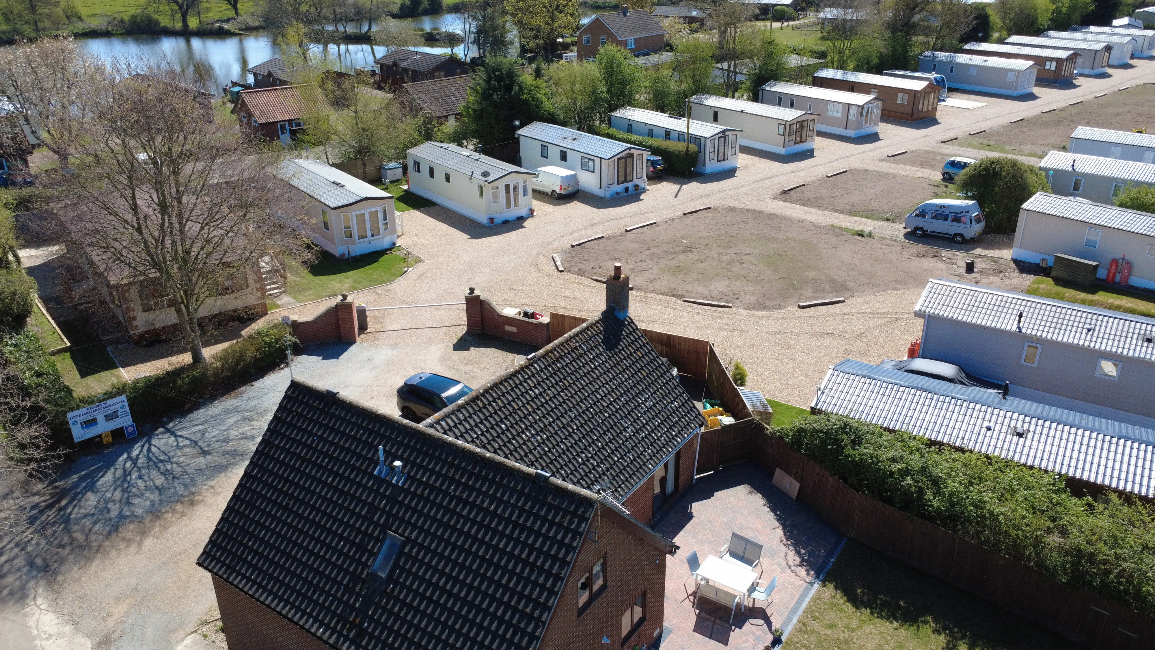 Aerial view of mobile home park with lake and brick houses nearby
