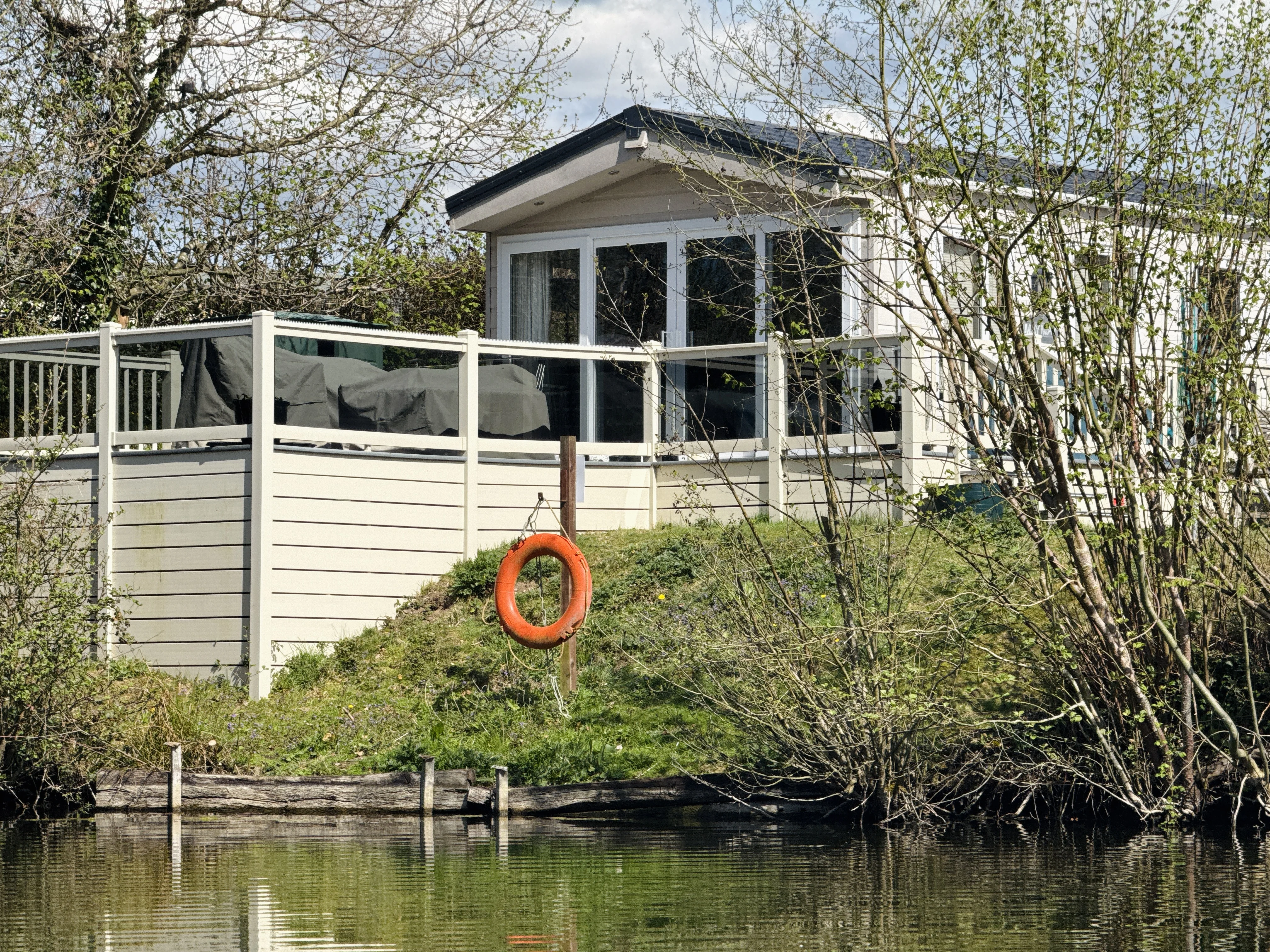 White lakeside cabin with orange life preserver hanging on wooden post