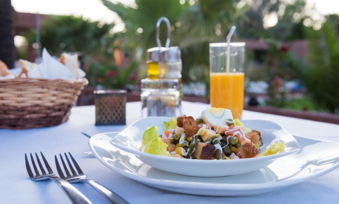 Elegant plate with salad and orange juice served in restaurant