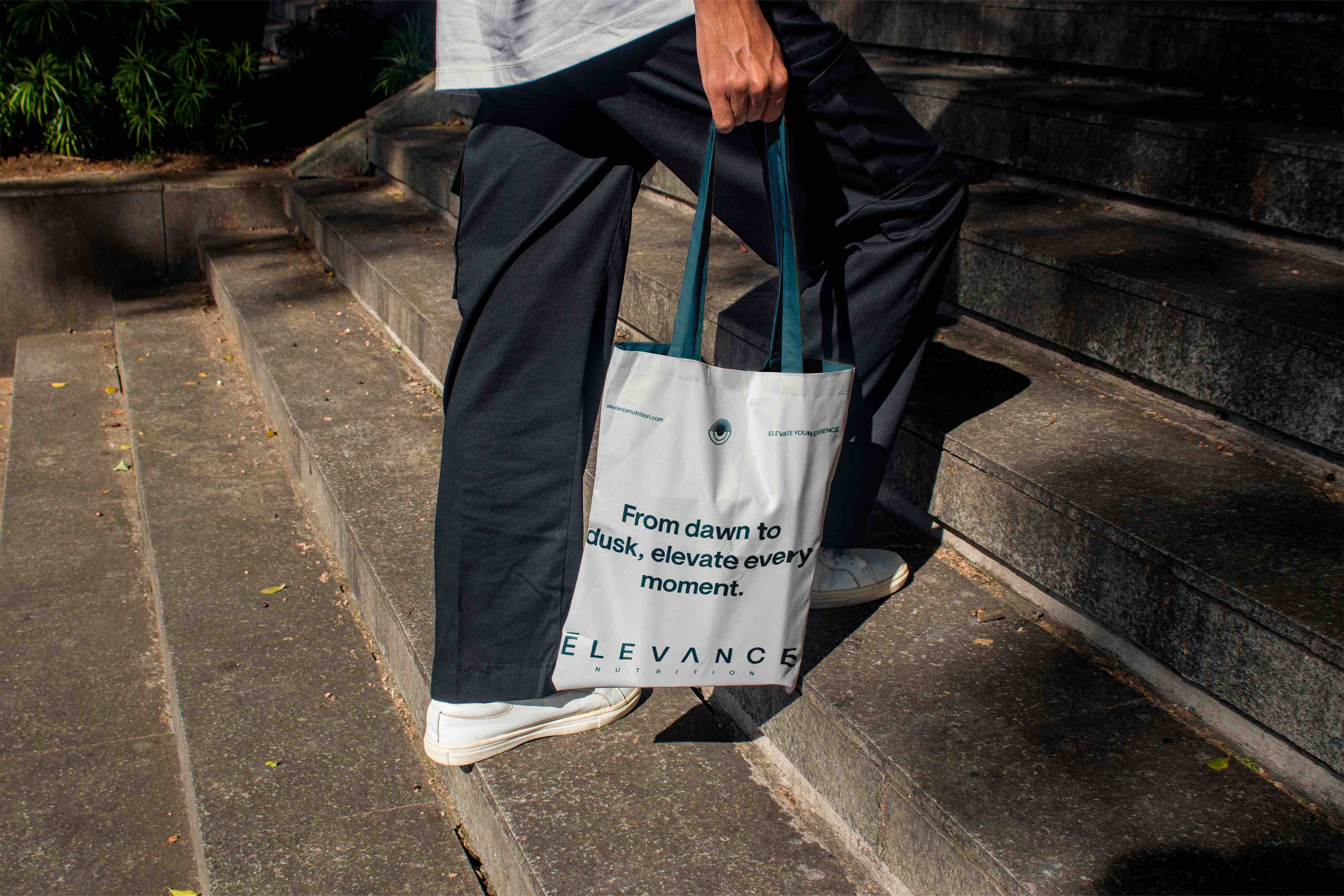 Una mano che tiene una borsa di tela blu con manici grigi e la scritta 'Organic Ingredients for a Healthy Life'.