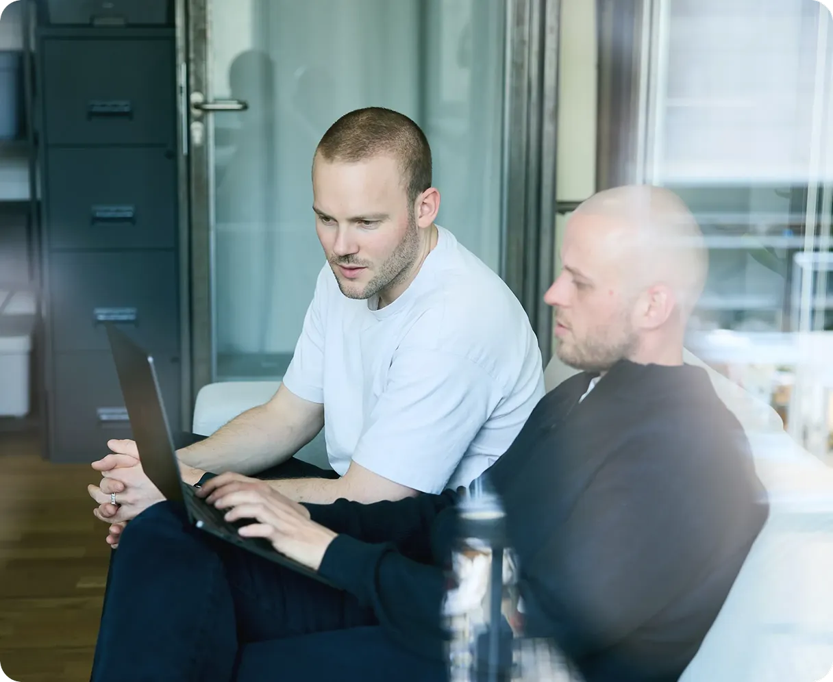 Mark and Sergei sitting at couch and looking at laptop