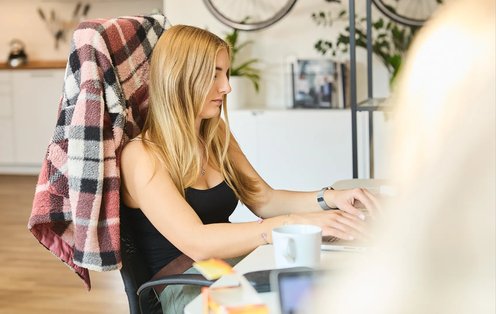 women sitting at office desk and typing on laptop