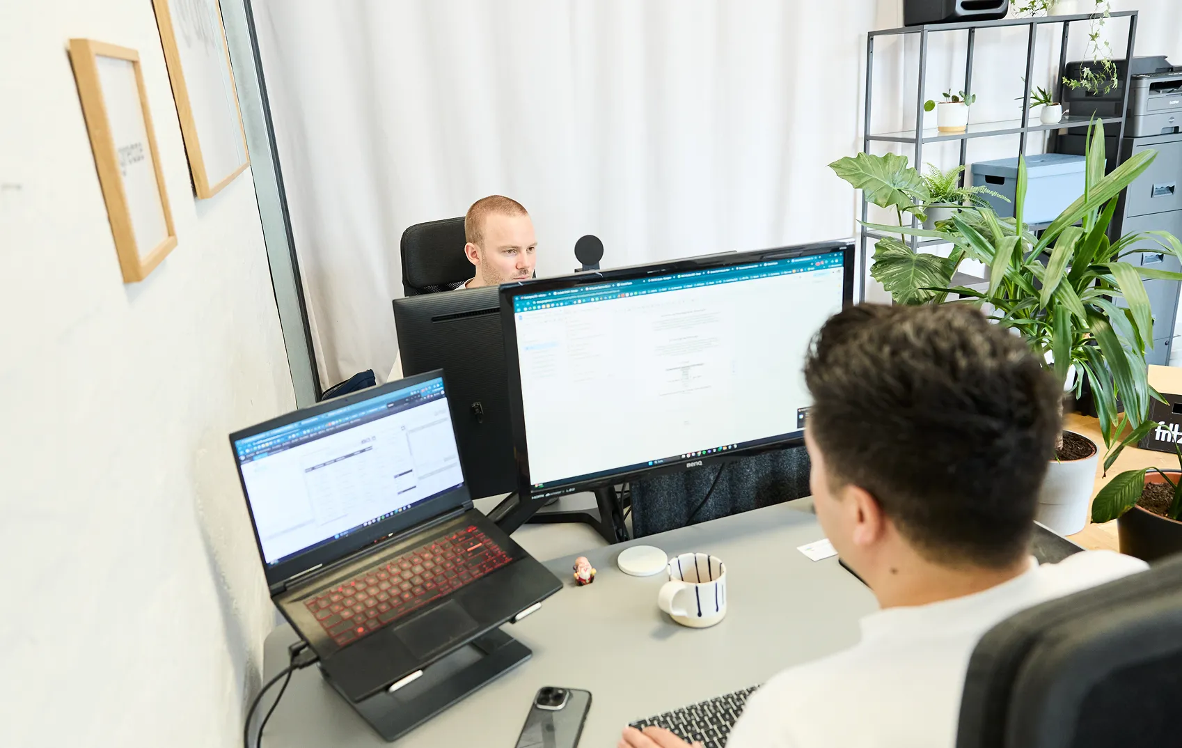 2 persons sitting at office desk and programming