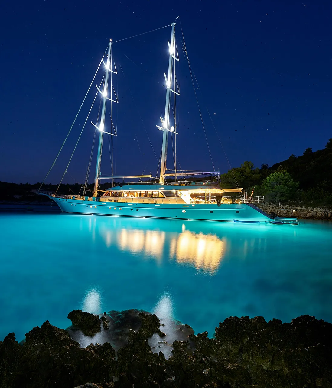 A yacht on clear blue water at night