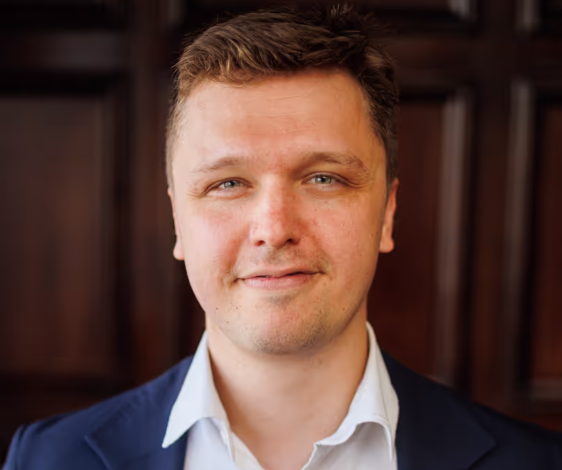 Professional headshot of a smiling man in a blue suit and white shirt
