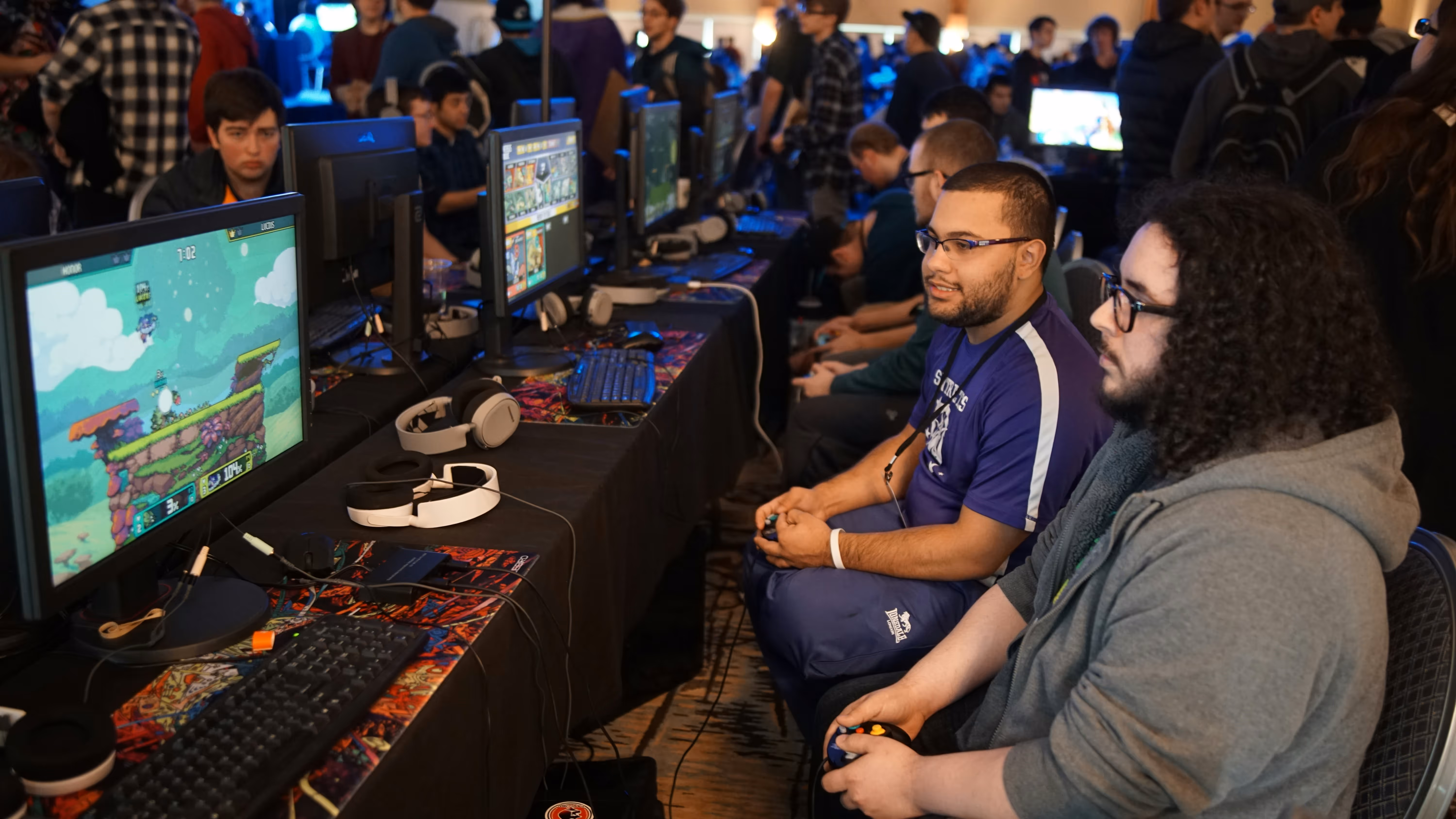 Gamers playing video games at a crowded esports event with multiple screens