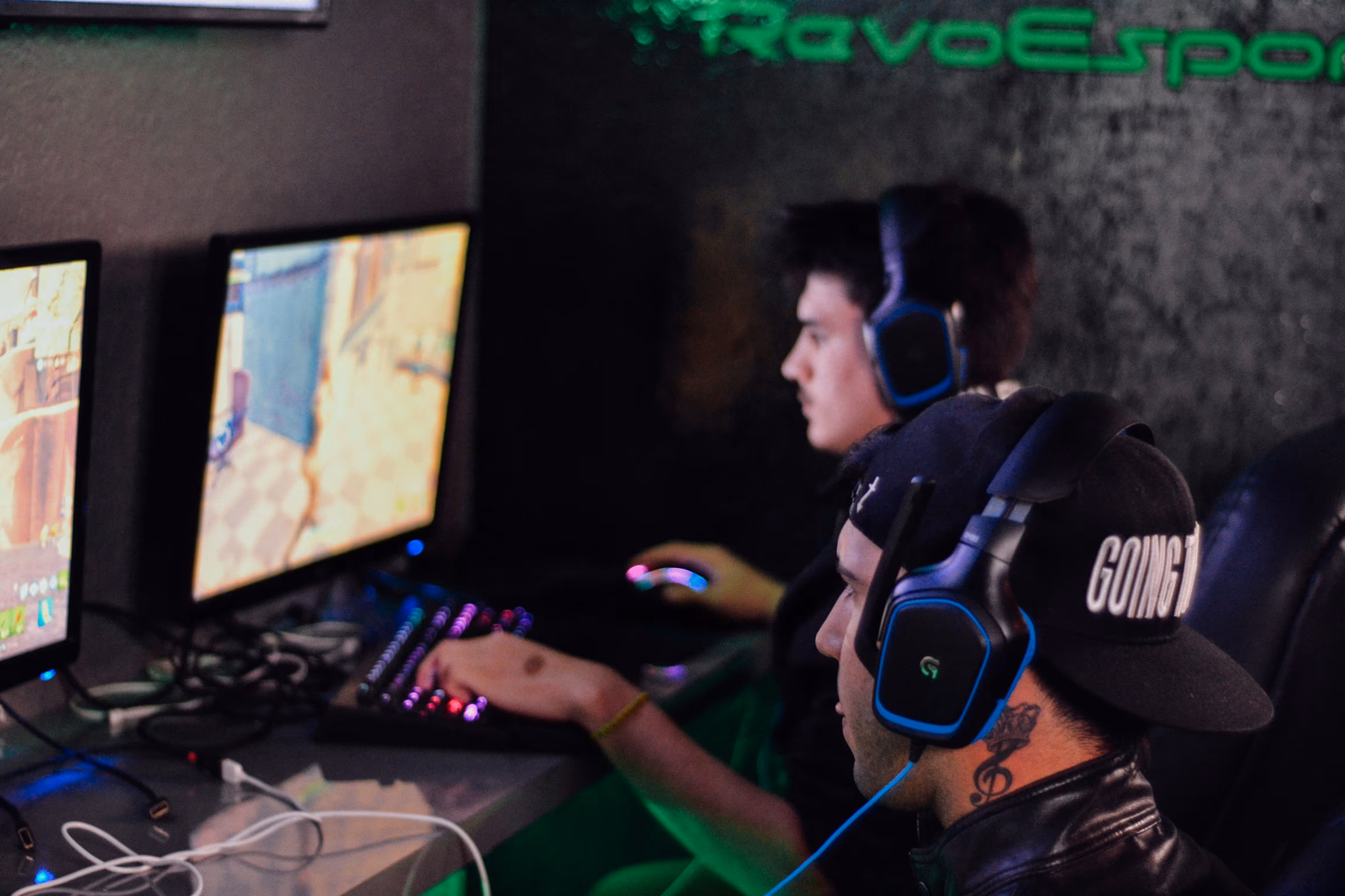 Gamers with headsets playing video games on computers with colorful RGB lighting