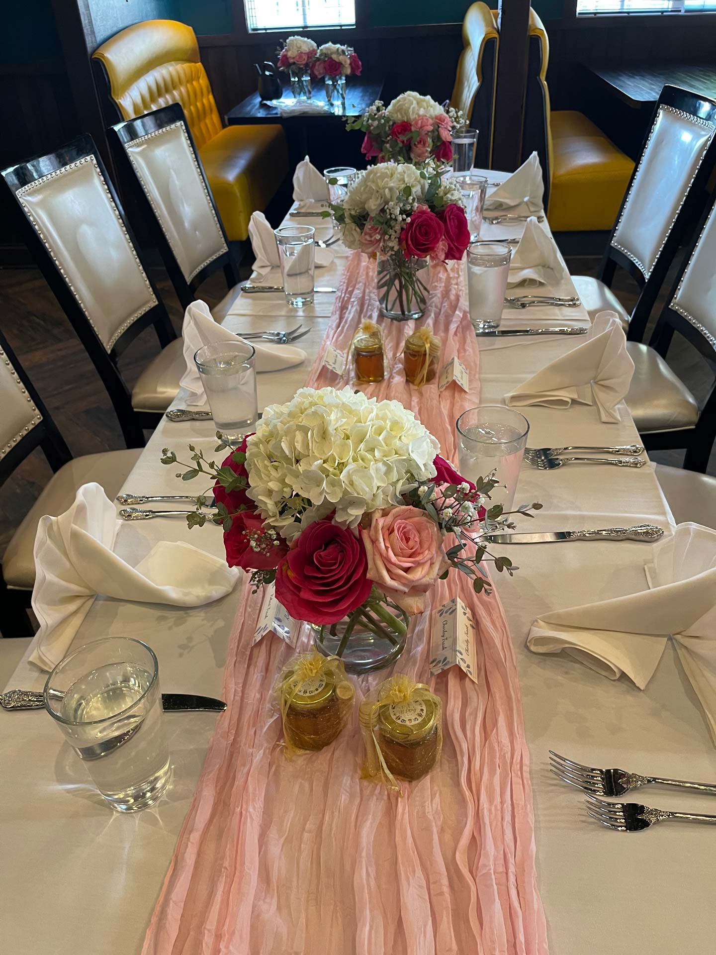 Elegant pink floral table setting with honey favors and napkins.
